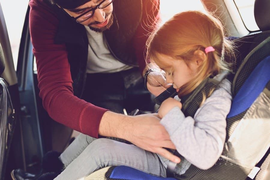 Safety first, father puts child in car seat