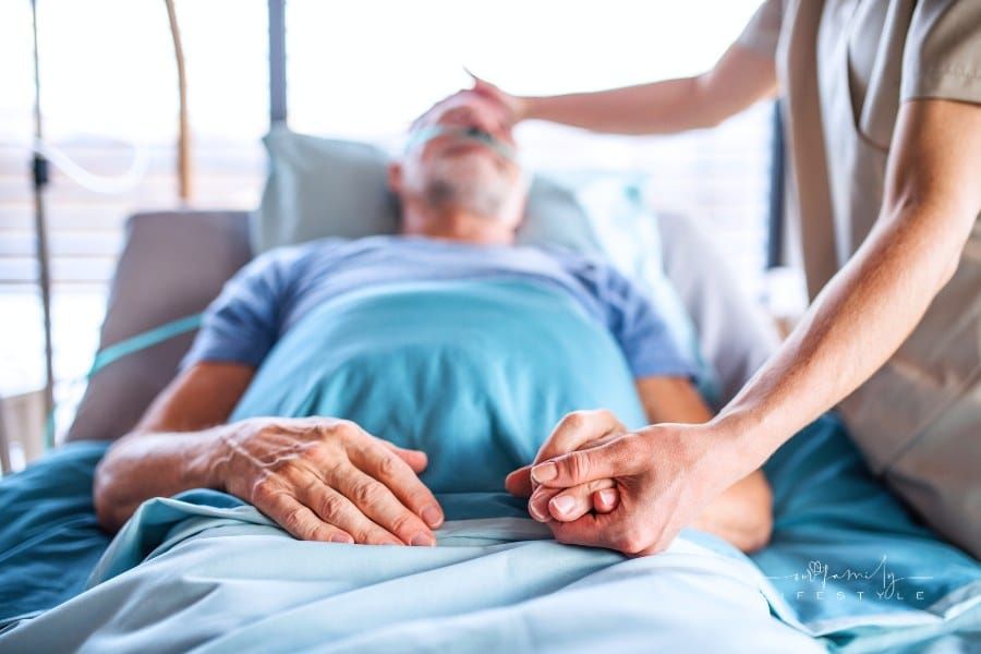 Doctor Holding Hand of Senior Man in Bed in Hospital