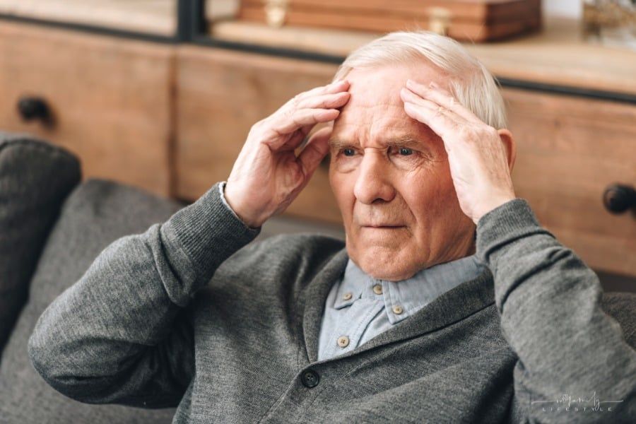 senior man sitting on couch trying to remember something