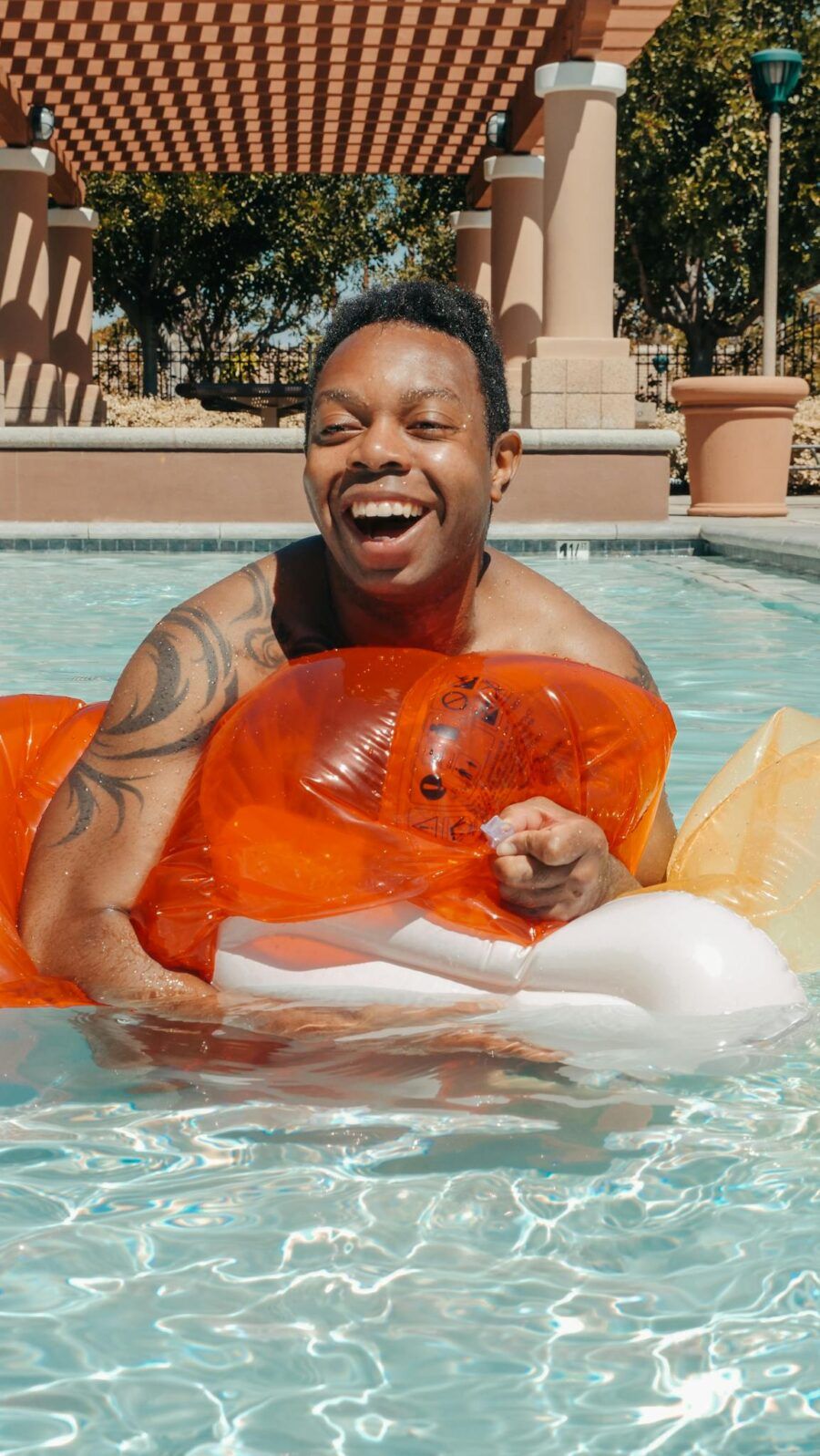 Smiling man enjoying a sunny day by the pool on a colorful float. Perfect for vacation themes.