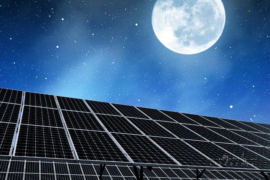 solar panels under a full moon in the night sky