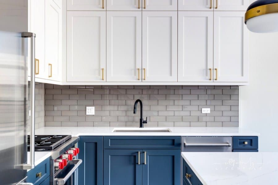 A kitchen detail with white and blue cabinets and a subway tile backsplash.