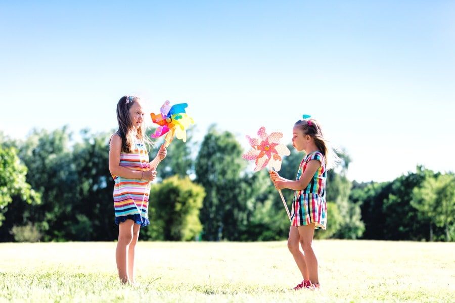 two children playing with pinwheels in the wind
