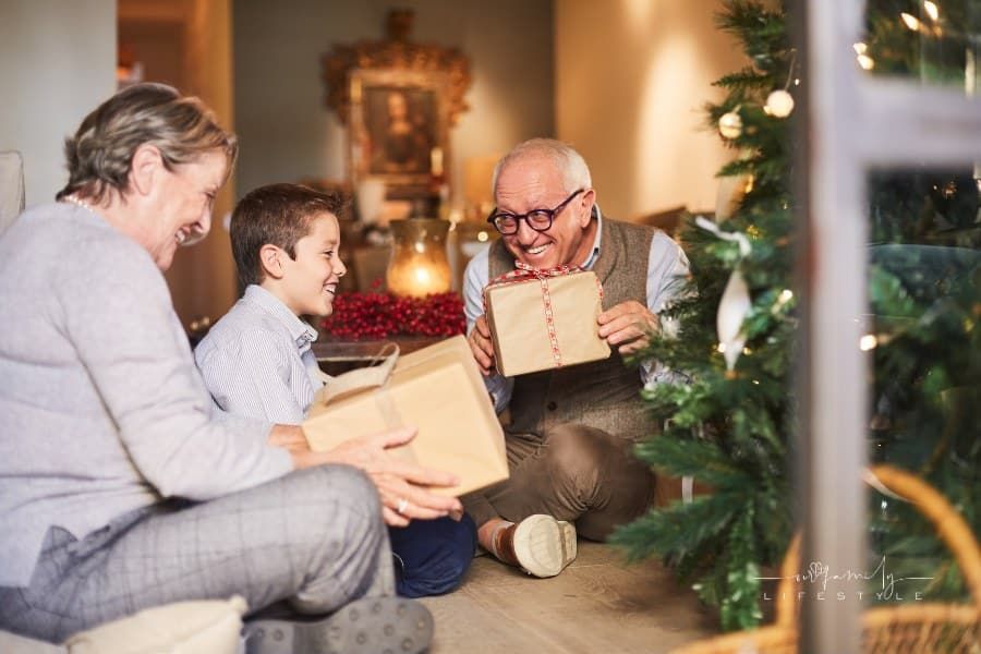 Grandparents and grandson unwrapping christmas gifts.