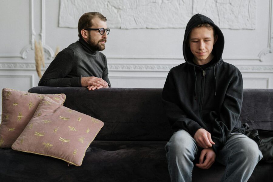 Teen in black hoodie during a therapy session in a calm indoor setting.