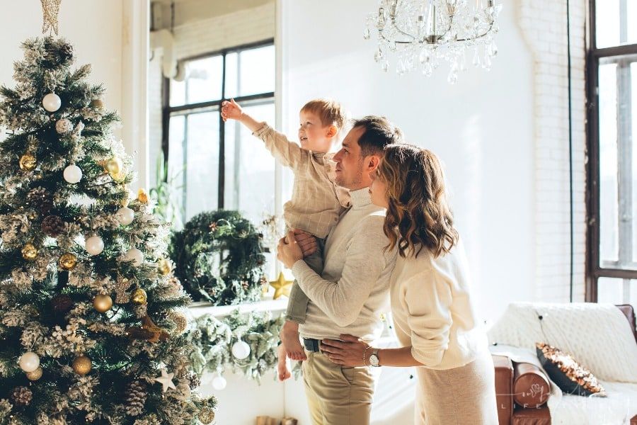 mom and dad looking a family Christmas tree with toddler son