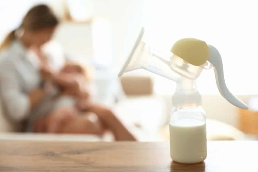 Mother Feeding Her Little Baby at Home, Focus on Breast Pump with Milk. Healthy Growth