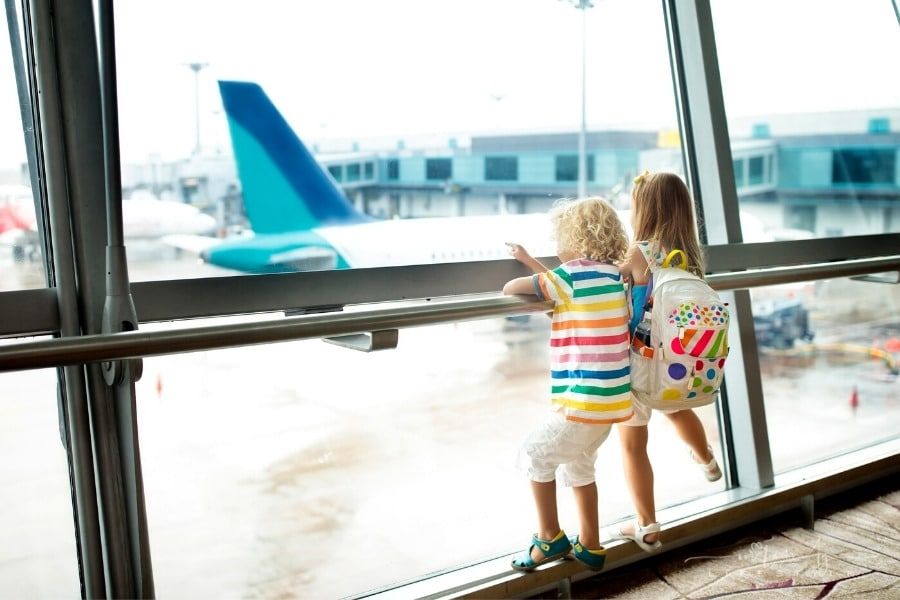 children wearing a backpack looking at planes at the airport
