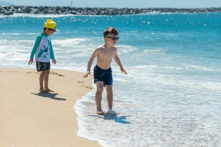 Two young boys enjoy a sunny day at the beach, playing near the ocean waves.