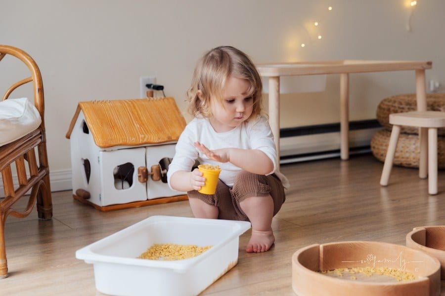 Girl Holding Yellow Plastic Cup Full of Macaroni for sensory bins