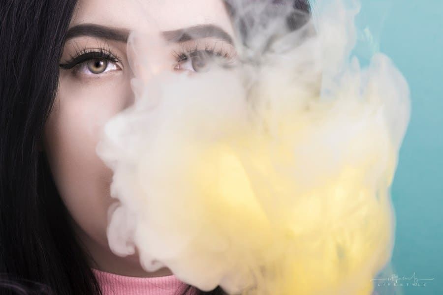 woman blowing colored smoke out of her mouth