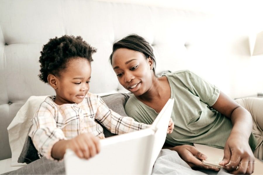 mom and toddler reading a book together on bed