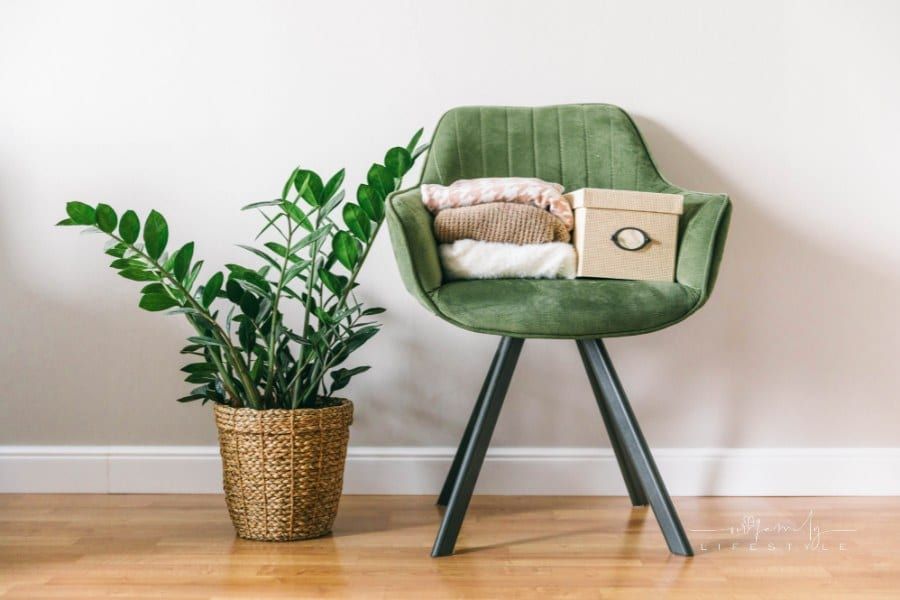 Stack of clothes on a green chair in a light room. Home space organization, spring cleaning and decluttering