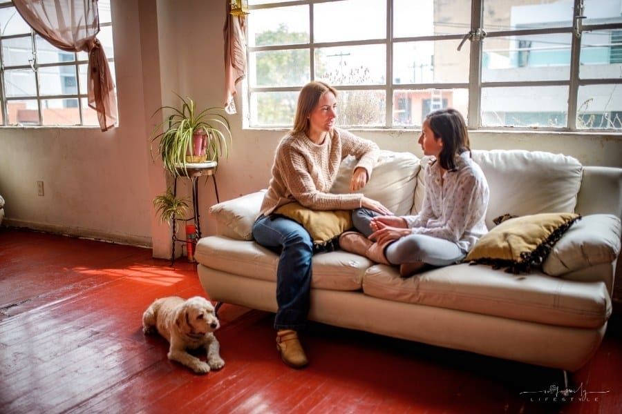 mother and daughter talking on couch with dogs at their feet