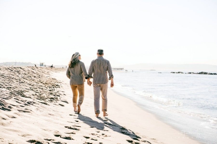 senior couple holding hands walking on beach