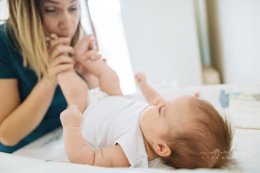 Millennial mother and newborn baby girl kissing and cuddling