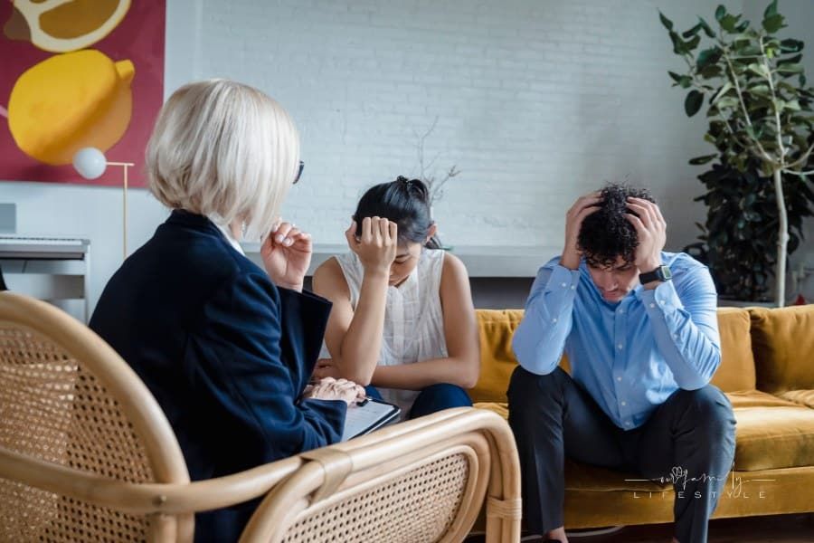 Young Couple Talking with a Therapist , sitting on a couch with their head in their hands