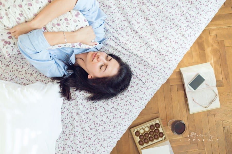 young woman laying on her bead holding a pillow while feeling depressed