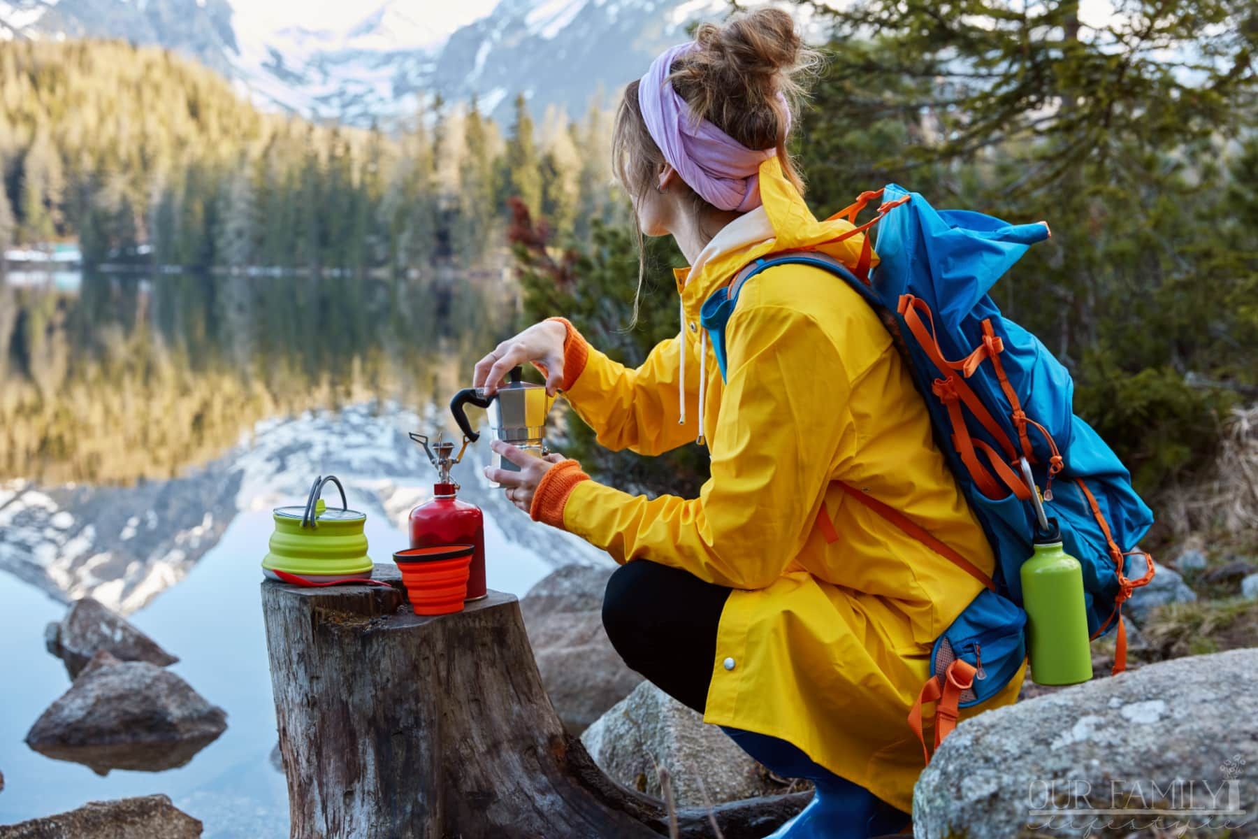 woman overlooking mountain lake with camping gear in hand
