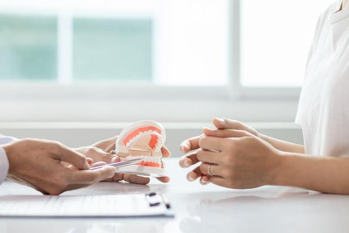 dentist showing tooth model to patient