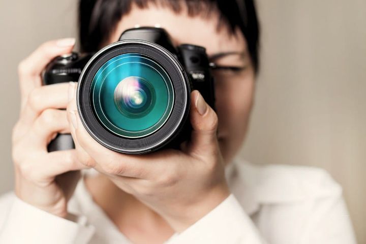 Woman Photographer with Camera in frront of her face