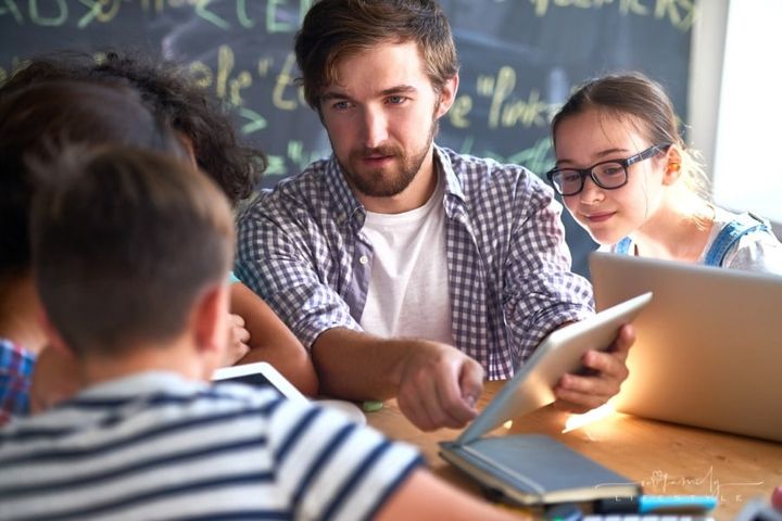 young teacher showing students lesson on tablet