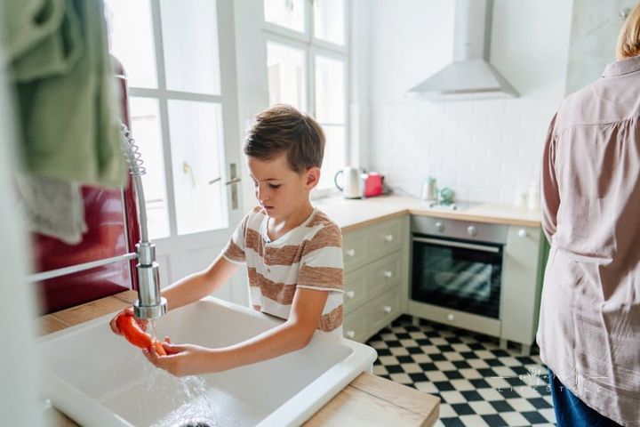 Photo of a little boy helping his grandmother in house chores