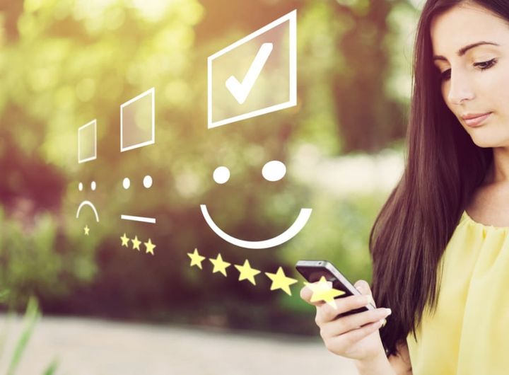 Businesswoman pressing face emoticon on virtual touch screen at smartphone .
