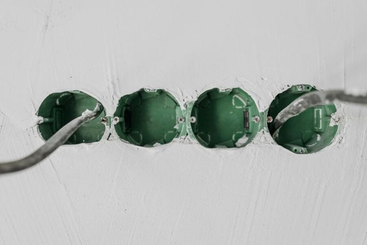 Close-up of green electrical boxes and wiring in a wall setup.