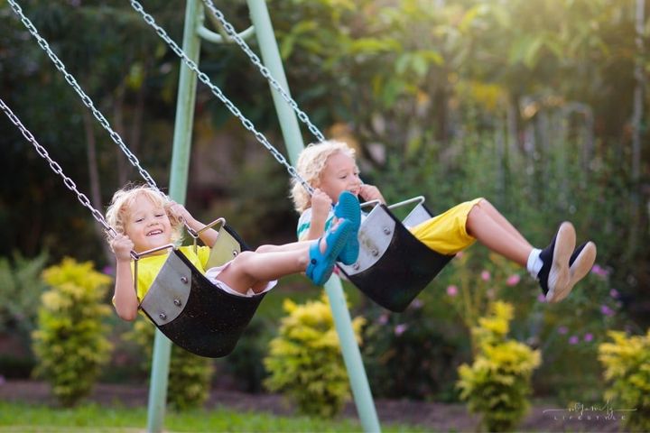 two boys swinging at a playground