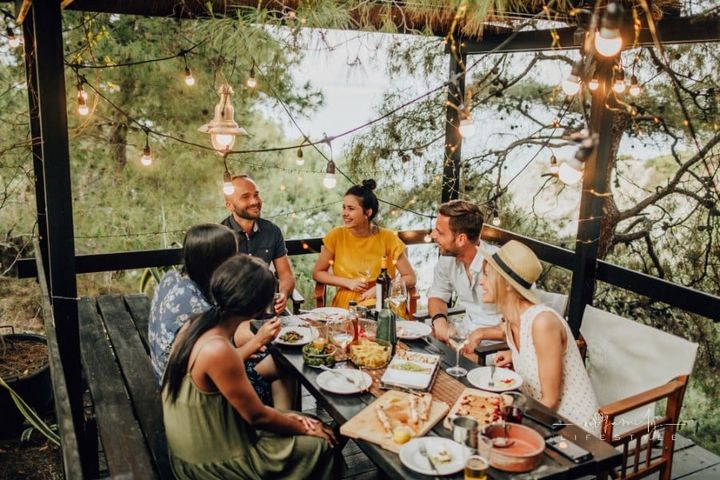 friends talking around a table at a summer dinner party by the water
