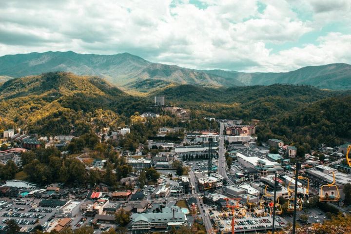 Explore the vibrant cityscape of Pigeon Forge with mountain backdrop from a captivating aerial view.