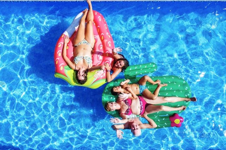 Happy Family Having Fun in a Swimming Pool on Floats