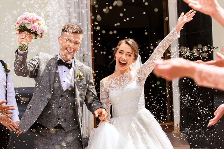 Happy wedding photography of bride and groom at wedding ceremony. Wedding tradition sprinkled with rice and grain as they lea