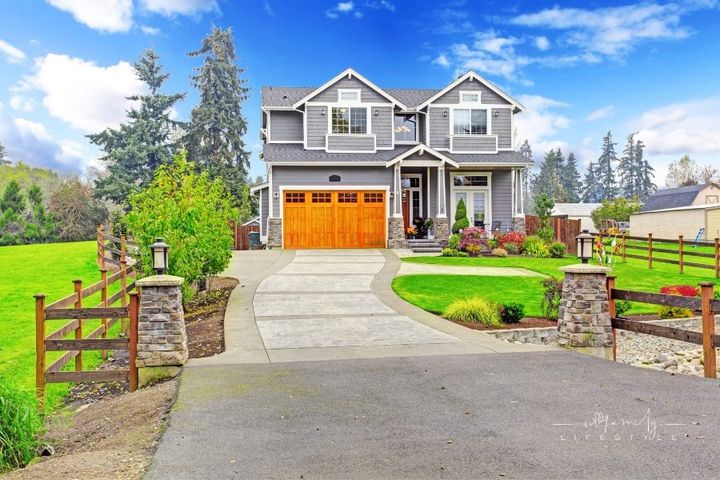 House exterior with column porch, wooden garage doors, and attractive curb appeal