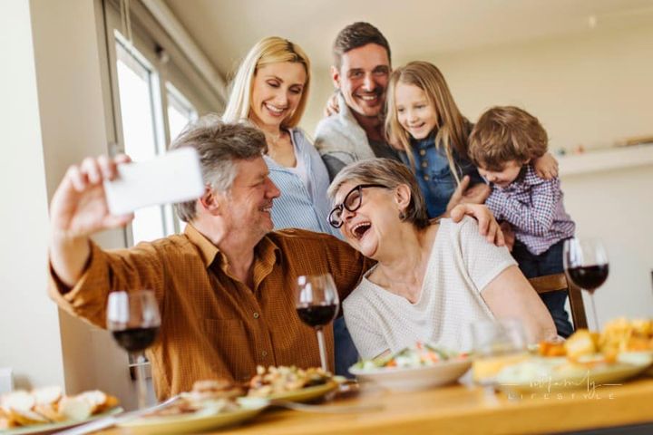Multi-generation family gathering at table for a picture together