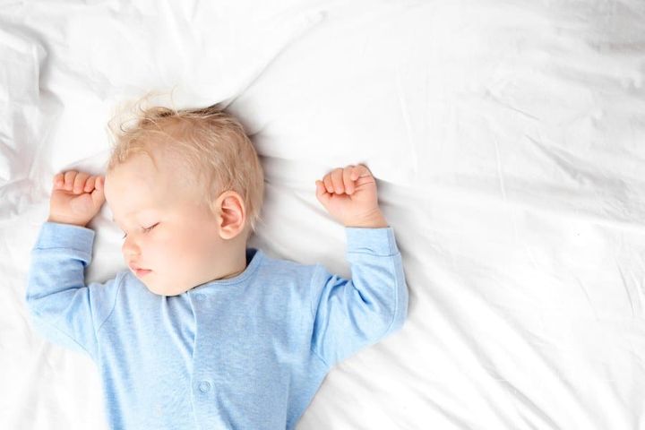 Baby boy sleeping on sed in blue pajamas
