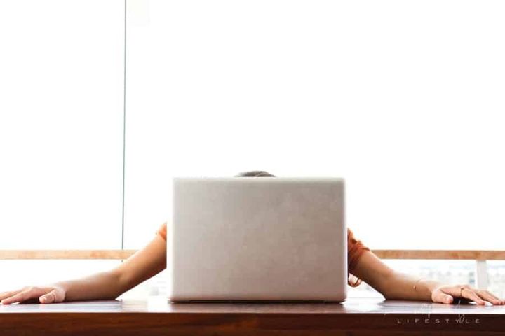 young frustrated woman with head rested on laptop and arms spread on desk
