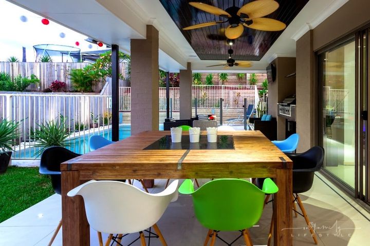 outdoor patio with large table, bright chairs, and outdoor kitchen