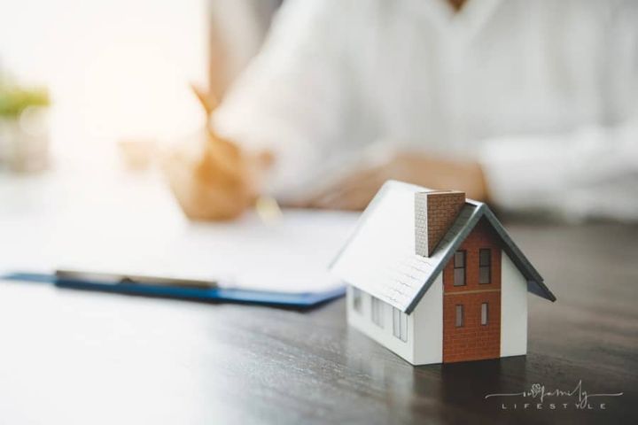 signing residential rental lease with small house figure in forefront