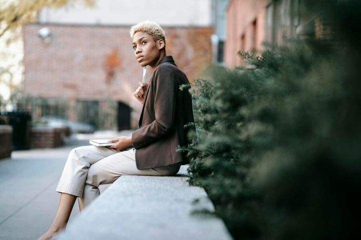Low angle side view of concentrated African American businesswoman touching chin with pen while attentively looking away