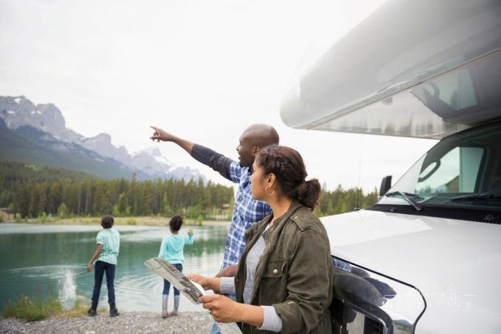 Family with map at RV near lake