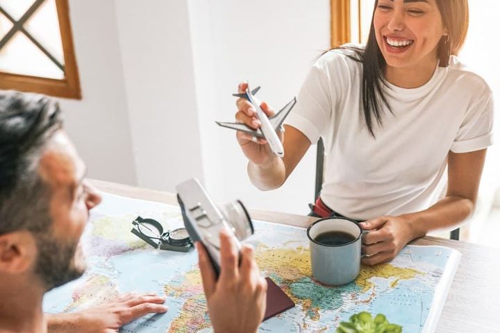 Happy couple having fun planning next world adventure together - Young people getting ready for next trip using a travel map