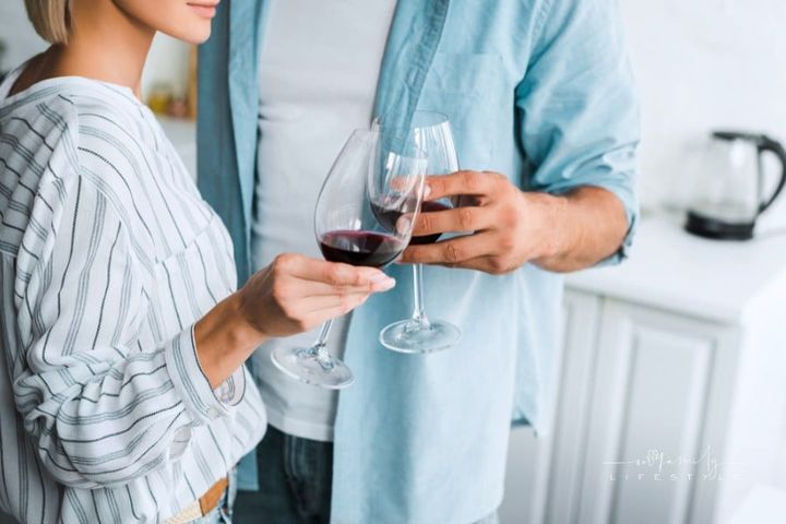 cropped image of young couple clinking with wineglasses in kitchen
