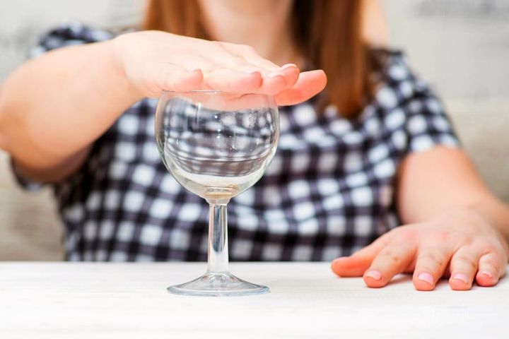 woman putting hand over wine glass to signal no more