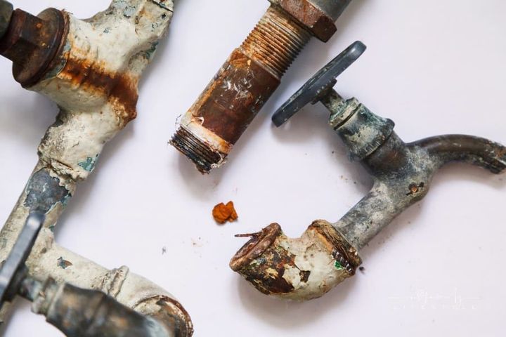 Dismantling of old pipes. Pieces of old rusty metal pipes and taps lie on a white background. Close-up