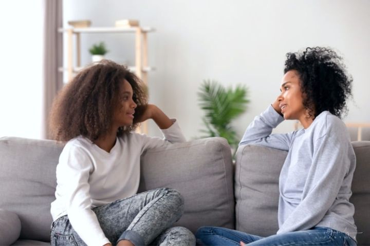 mom and teenage daughter having a conversation on the couch