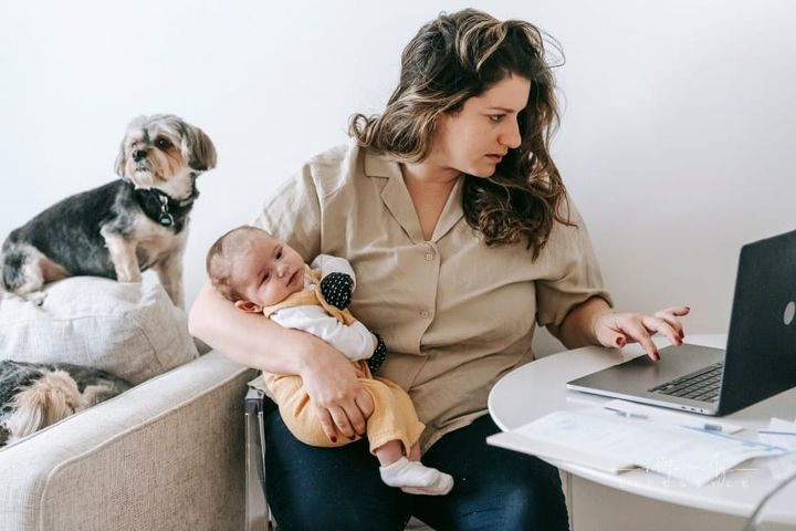 Mother Carrying Her Baby while Working From Home