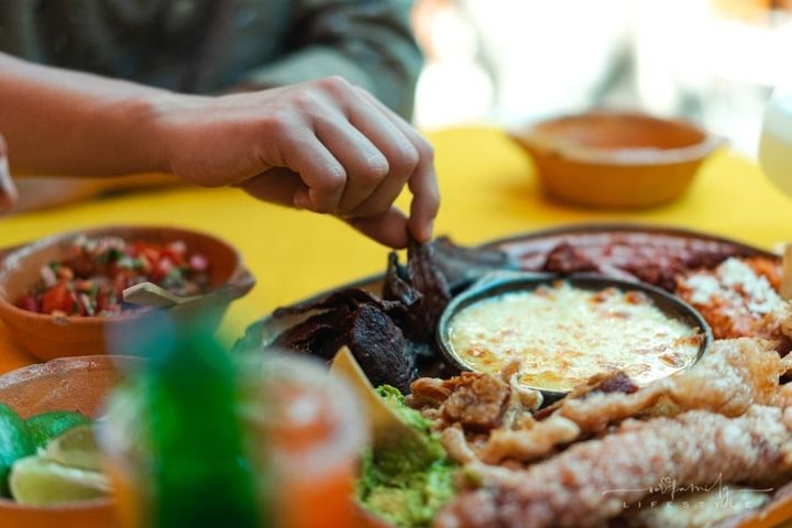man's hand grabbing a piece of Mexican food dish