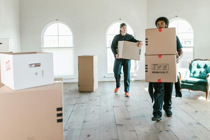 Two movers carrying boxes in a sunlit room, ready to assist with relocation.